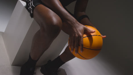 Nahaufnahme-Eines-Sitzenden-Männlichen-Basketballspielers-Mit-Händen,-Die-Ball-4-Halten